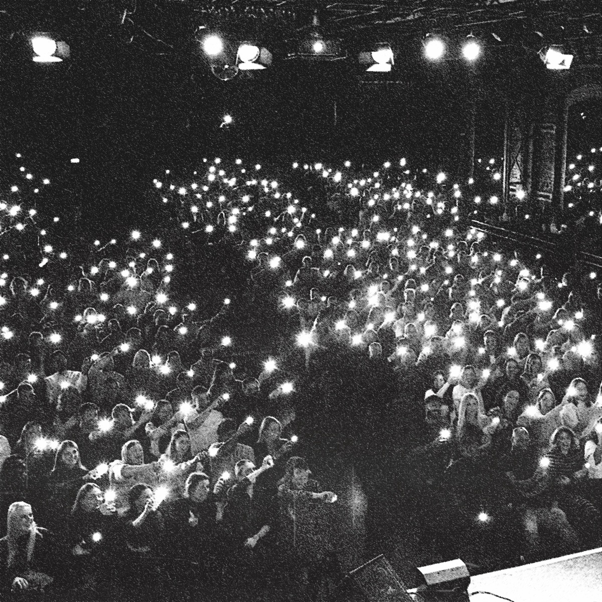 Saal voller Menschen mit leuchtenden Handylichtern, Schwarz-Weiß-Foto
